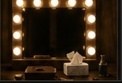 A dressing-room mirror surrounded by warm bulbs.